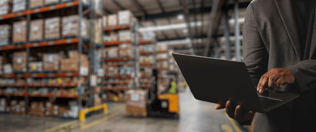 Operations manager reviewing logistics on a laptop in a warehouse